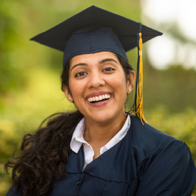 A smiling graduate in a cap and gown celebrating academic success, representing career opportunities built through the admission procedure for travel and tourism that prepares students for the professional world.